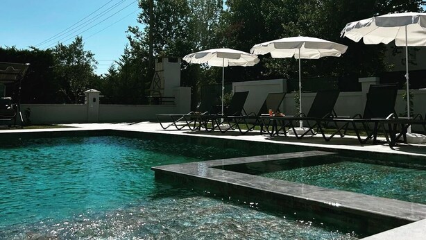 A swimming pool with clear water, surrounded by lounge chairs and umbrellas, under a sunny sky. - Safe, central, lux and comfortable holiday in Dalyan. (Dalyan)