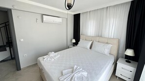 A hotel room with a large bed, two bedside tables, a wall-mounted air conditioner, and a staircase leading to another level. - Safe, central, lux and comfortable holiday in Dalyan. (Dalyan)