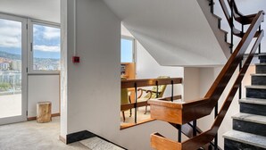 Et moderne interiør med en trappe i træ, store vinduer og udsigt over byen.