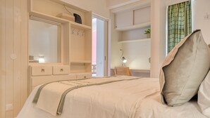 Et soveværelse med seng, garderobe, skrivebord og et vindue med gardiner.