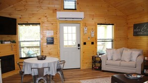 A cozy log cabin interior with a dining area, a sofa, and a fireplace.