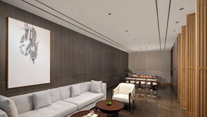 A modern lounge area with a grey sofa, two round wooden tables, and a white armchair. - Ramada by Wyndham Taizhou West (Taizhou)