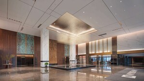 A spacious lobby with a modern chandelier, a reception desk, and a large, decorative column. - Ramada by Wyndham Taizhou West (Taizhou)