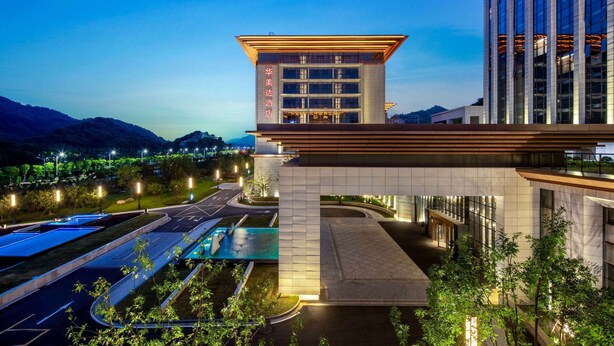 A hotel with a modern design, featuring a prominent entrance and a pool area. - Ramada by Wyndham Taizhou West (Taizhou)