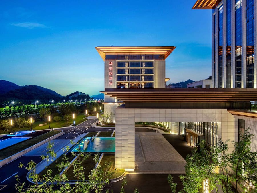 A hotel with a modern design, featuring a prominent entrance and a pool area.