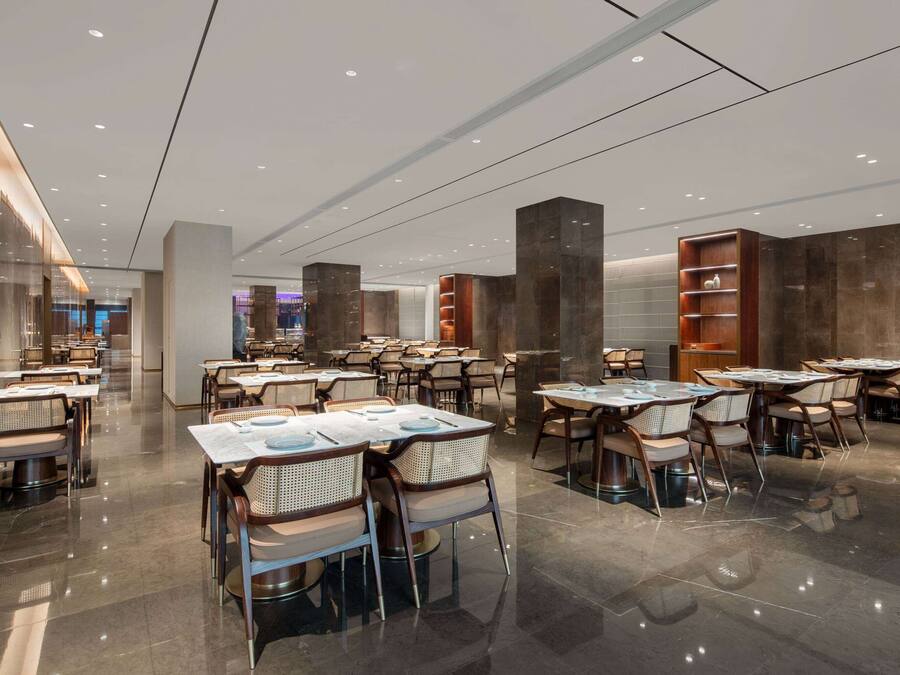 Un restaurant moderne doté de nombreuses tables et chaises, d’un sol ciré et d’un éclairage contemporain.