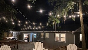 Un área de estar al aire libre con sillas tipo Adirondack, suelo de grava y un edificio con ventanas.