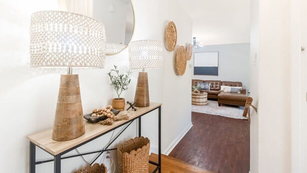 Un salón moderno con un sofá de cuero marrón, una mesa de centro y un espejo grande sobre una consola decorada con objetos ornamentales.