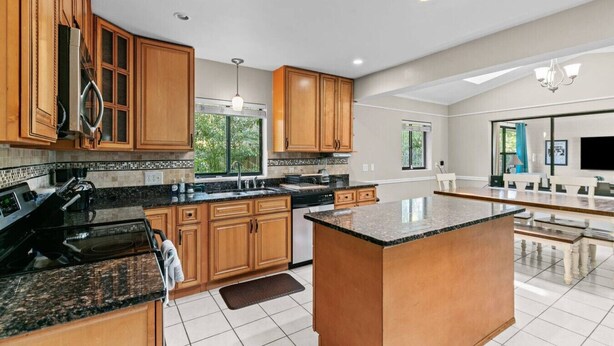 A spacious kitchen with wooden cabinets, granite countertops, and a large island.