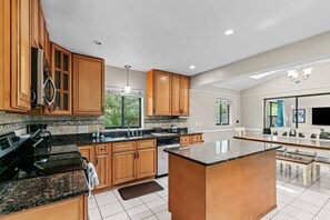 Una cocina amplia con armarios de madera, encimeras de granito y una isla grande.