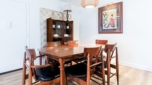 A dining area with a wooden table and chairs, a cabinet with glass doors, a hanging light fixture, and a framed picture on the wall. - 1 Bedroom Condo: Walk to Shands / UF / VA- Pool! (Gainesville)