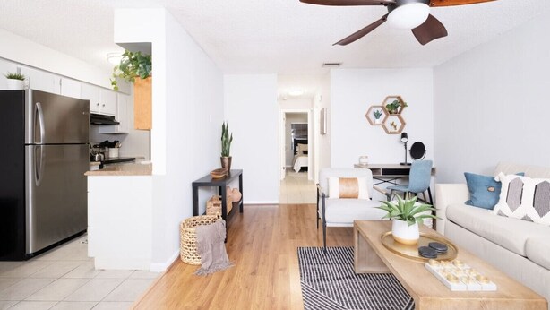 Une cuisine moderne dotée d’un réfrigérateur encastré, un coin repas avec une table et des chaises, et un salon avec un canapé et une table basse.