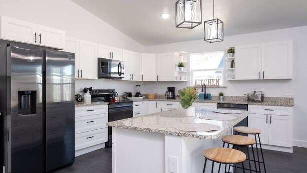 A modern kitchen with white cabinets, stainless steel appliances, granite countertops, and pendant lighting. - New Home- Sleeps 8 -Near Gainesville & Springs (High Springs)