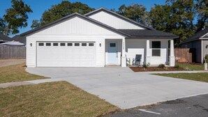 A single-story house with a garage, a front porch with two chairs, and a small garden area. - New Home- Sleeps 8 -Near Gainesville & Springs (High Springs)