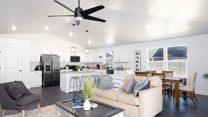 A modern kitchen with white cabinets, a stainless steel refrigerator, and a central island with bar stools. - New Home- Sleeps 8 -Near Gainesville & Springs (High Springs)
