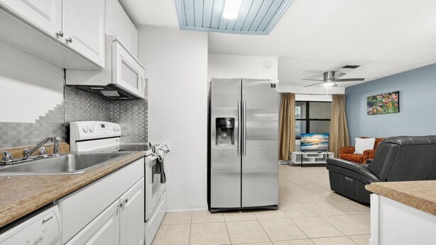 A modern kitchen with white cabinets, a stainless steel refrigerator, and a built-in oven. - Downtown Duplex- Spacious and Comfy 2 Bedroom (Gainesville)