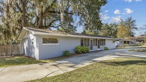 A single-story house with a front porch, a small front yard, and a large tree with Spanish moss. - Downtown Duplex- Spacious and Comfy 2 Bedroom (Gainesville)