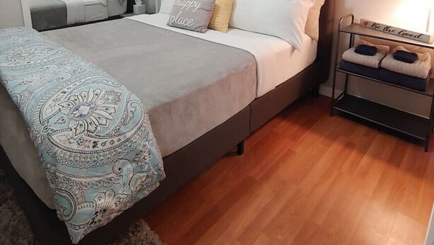 A bedroom with a bed, bedside tables, a nightstand, a mirror, and a large beach-themed painting on the wall. - Centrally located 2 bedroom condo for 6 people (Gainesville)
