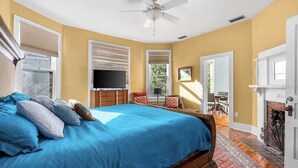 Ein Schlafzimmer mit einem großen Bett, einem Deckenventilator, einem Fernseher und einem Kamin.