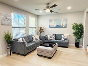 Un salon moderne avec un canapé d’angle, une table basse et un ventilateur de plafond.