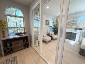 A modern living room with a large window, a wooden cabinet, and a patterned armchair. - Location! Location!  Woodbury-Walking to Shopping and Activities 步行到商圈，活動中心 (Irvine)