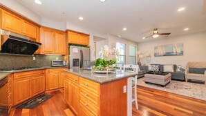 A modern kitchen with wooden cabinets, granite countertops, and a central island. - Location! Location!  Woodbury-Walking to Shopping and Activities 步行到商圈，活動中心 (Irvine)