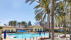 A pool area with palm trees, a swimming pool, and a building with a tiled roof. - Location! Location!  Woodbury-Walking to Shopping and Activities 步行到商圈，活動中心 (Irvine)