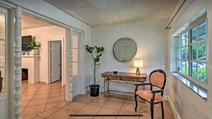 Quarto com mesa de madeira, cadeira, planta em vaso, espelho e janela.
