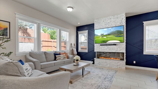 A modern living room with a fireplace, a large TV, and a comfortable seating area. - Flagstaff Retreat w/ Hot Tub • Firepit • Dogs OK - 1 mi to NAU (Flagstaff)