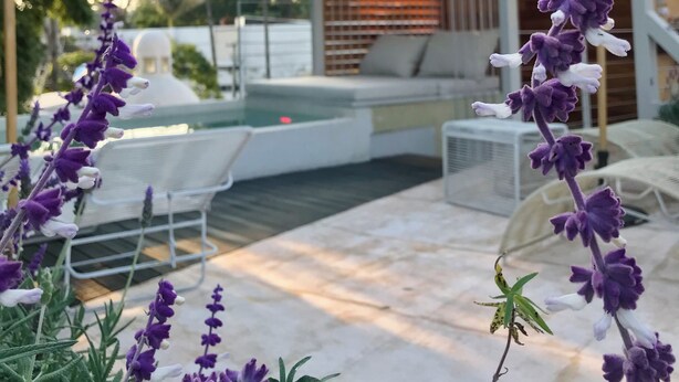 Un patio con mobiliario exterior, piscina y un espacio de descanso cubierto.