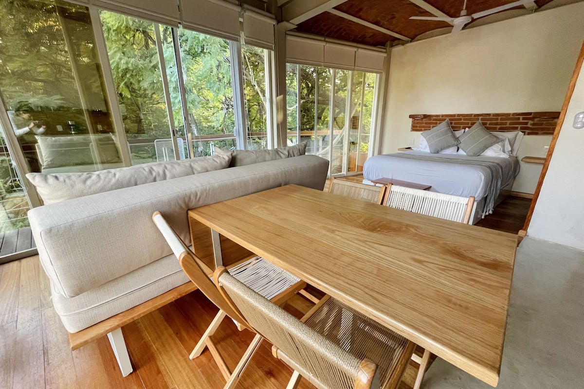 A modern room with a wooden table, a sofa, and a bed.