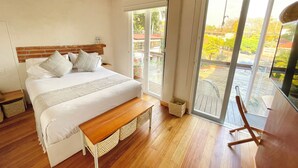Un dormitorio con una cama grande, suelo de madera y un balcón con vistas.