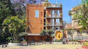 Un edificio de varios pisos con fachada de ladrillo, balcones y un patio central con una fuente.