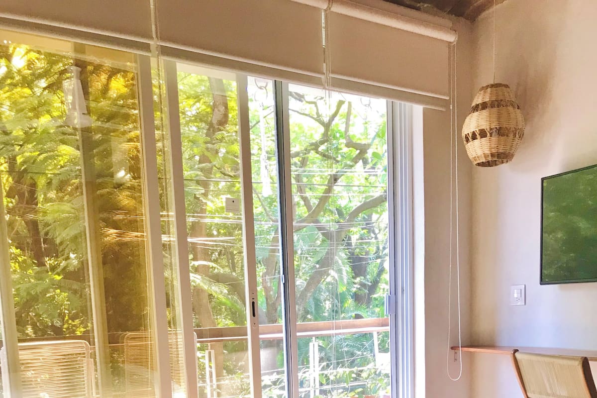 A bedroom with a bed, a window with a view of trees, and a hanging light fixture.