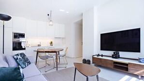 A modern living room with a grey sofa, a coffee table, and a TV mounted on the wall.