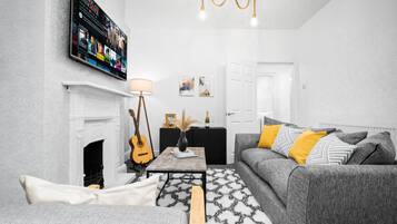 A living room with a fireplace, a television mounted on the wall, a sofa, and a coffee table.