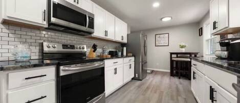A modern kitchen with white cabinets, stainless steel appliances, and a tiled backsplash.