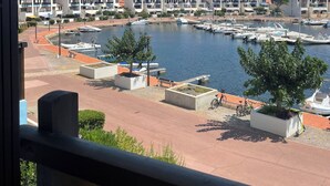 Een jachthaven met aangemeerde boten, een heldere blauwe lucht en moderne gebouwen op de achtergrond.