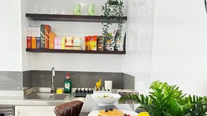 A modern kitchen with a dining table, chairs, and a variety of food items. - Apt. 04 -  Seaside Serenity Chic Studio Steps to Promenade (Brighton and Hove)