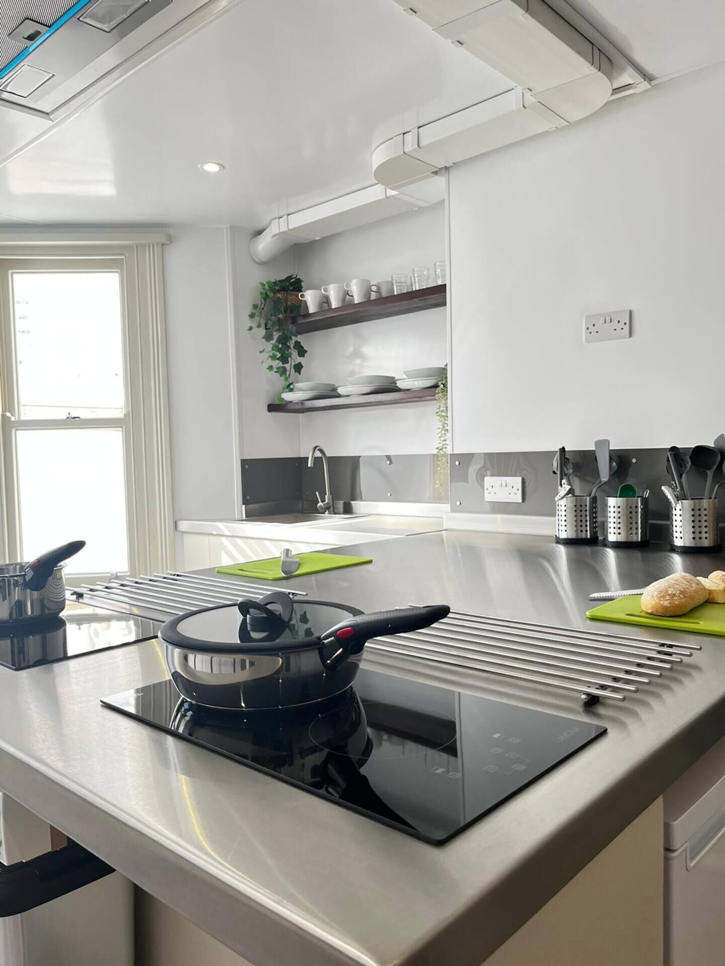 A modern kitchen with a built-in stove, a sink, and a countertop with various kitchen items.