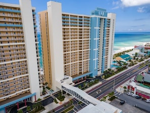 Ein mehrstöckiges Hotel mit einer zentralen Innenhöfe, einem Parkplatz und Blick auf den Strand.