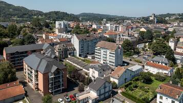An aerial view of a town with a mix of residential and commercial buildings, including a prominent tower and a castle-like structure on a hill.