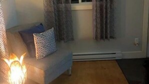 A cozy living room with a sofa, patterned curtains, a clock, and a fireplace.