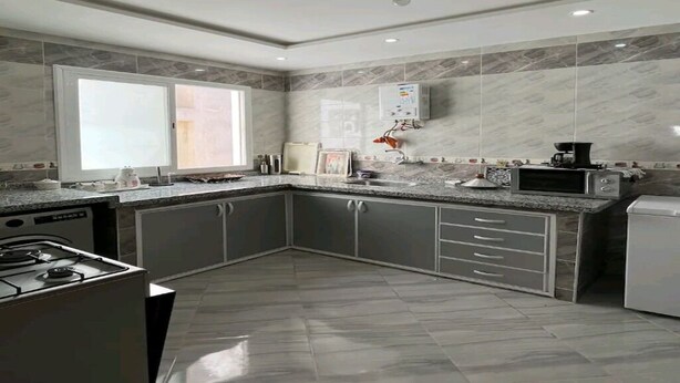 Una cucina moderna con mobili grigi, piano cottura integrato e forno a microonde.