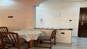 Zona pranzo con tavolo e sedie, isola della cucina e una porta.