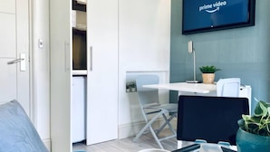 A modern living room with a flat-screen TV displaying 'prime video', a coffee table with a cup, a sofa, and a dining area with a table and chairs. - Apt. 05 - Stylish Studio Steps from Sea, Bars & Promenade (Brighton and Hove)