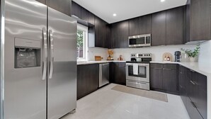 A modern kitchen with dark wood cabinets, stainless steel appliances, and a water dispenser.
