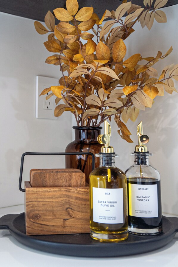 Una encimera de cocina con un florero de hojas secas, una caja de madera y dos botellas de aceite de oliva y vinagre balsámico.