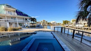 A swimming pool with a wooden deck, a boat dock, and a building with solar panels.