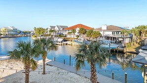 A marina with boats docked, a pool, and a beach area with palm trees.
